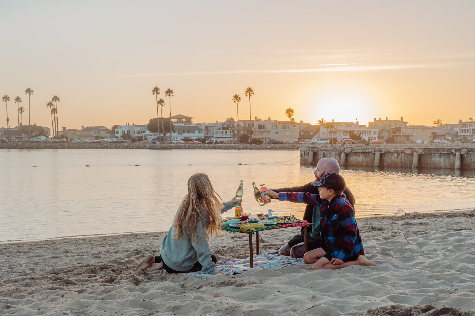 A family sharing a picnic beside the harbor at sunset